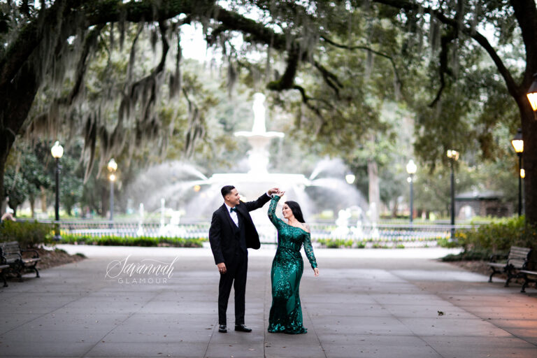 A couple in a green dress dancing in front of a fountain in charleston, south carolina.