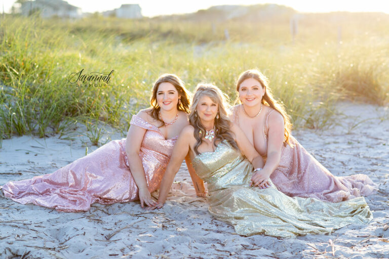 Three girls in gold dresses posing on the beach.