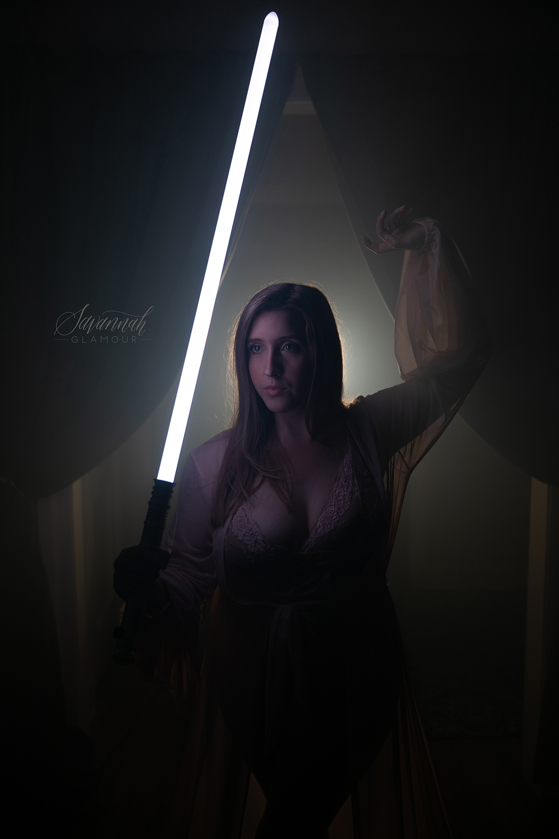 portrait of woman in a sheer dress holding a lightsaber