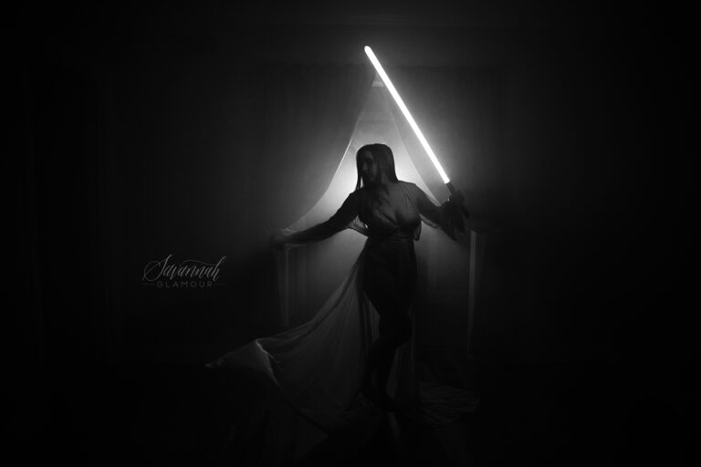 A woman holding a light saber in the dark.