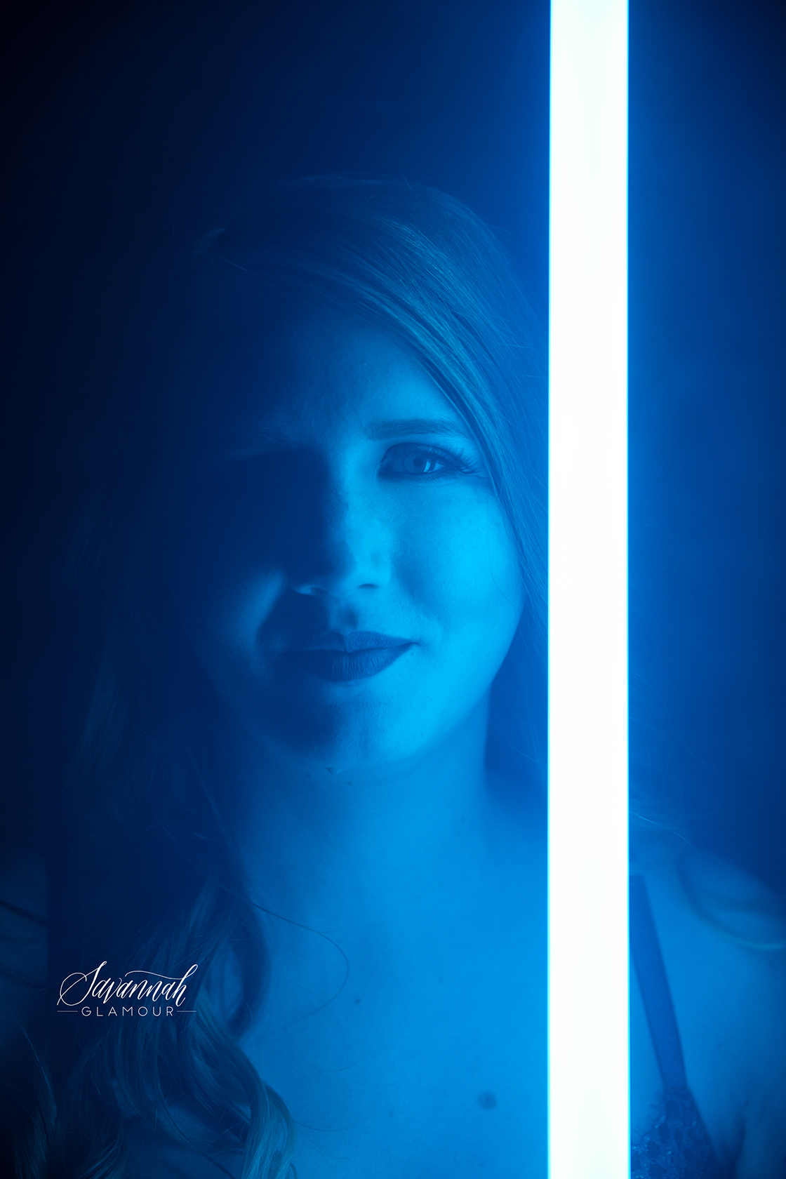 headshot of a woman holding a lightsaber close to her face