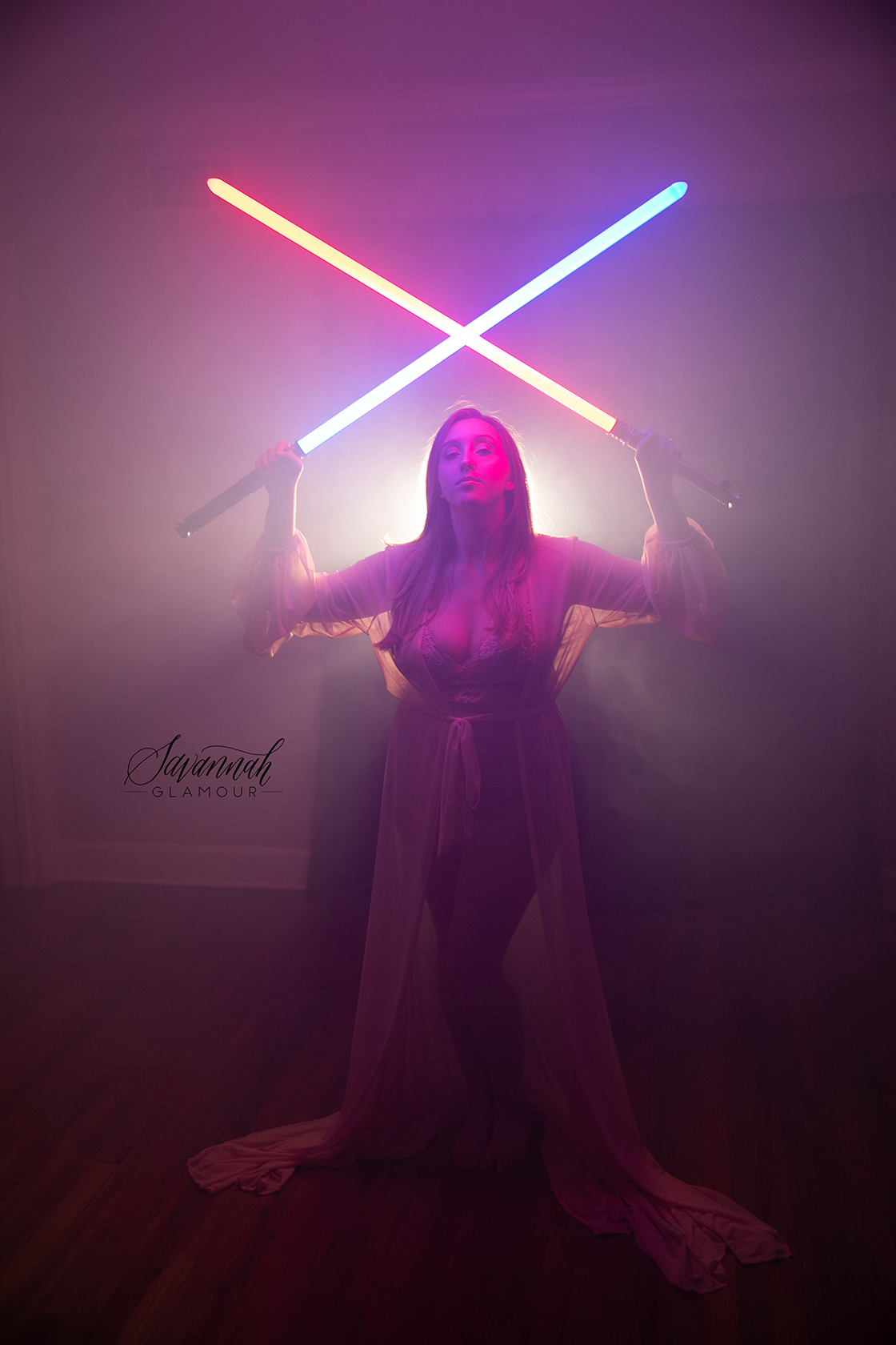 woman in a sheer dress posing with 2 lightsabers over head