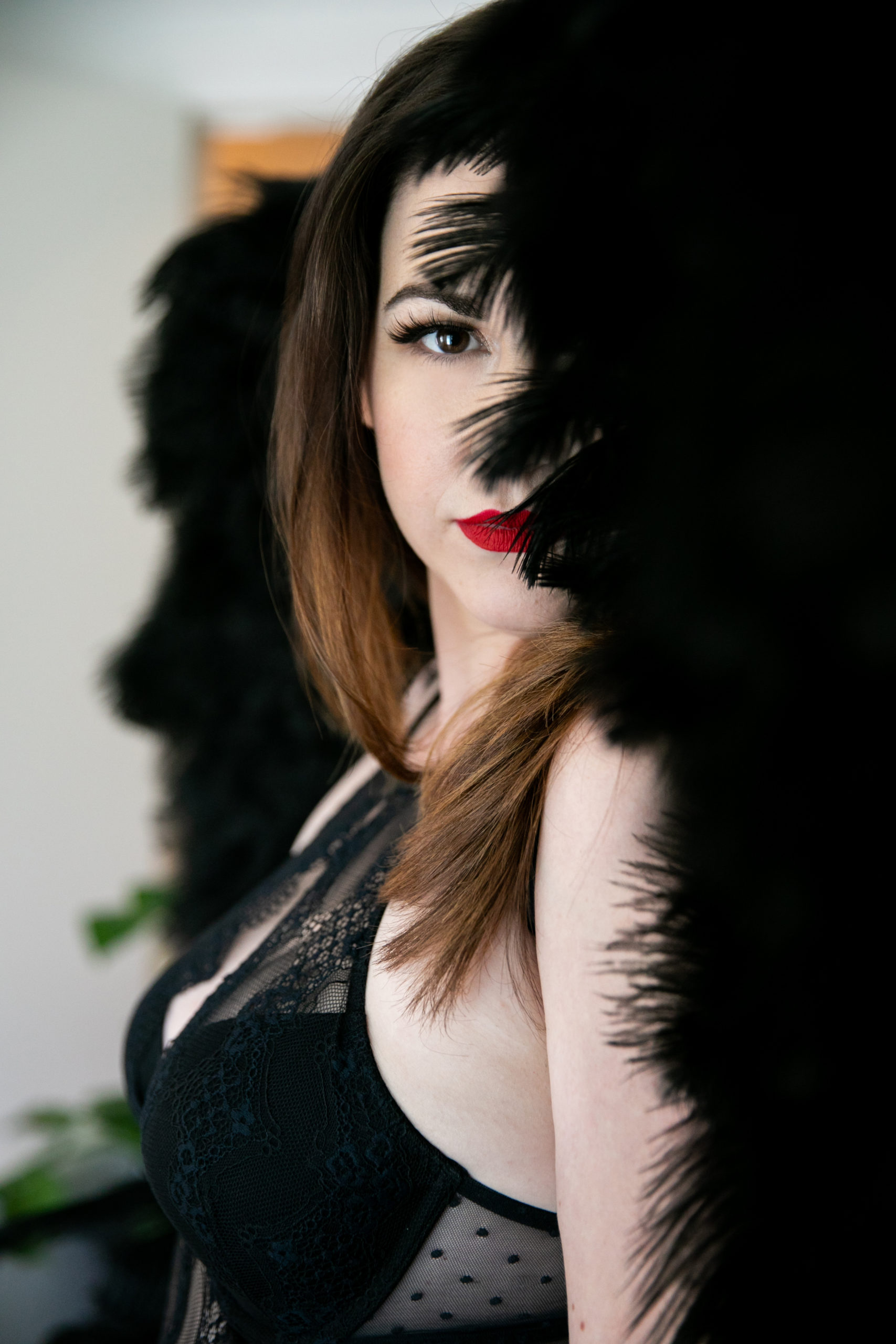 portrait of woman in lingerie wearing black angel wings partially covering her face