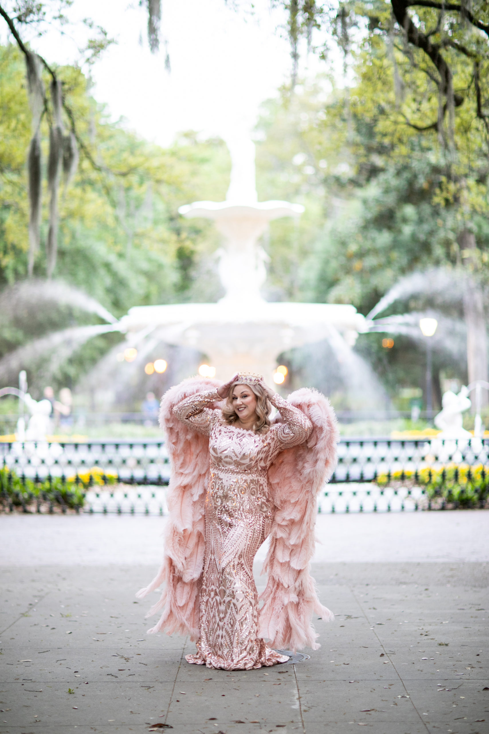 woman posing in front of Savannah fountain wearing crown, gown and angel wings