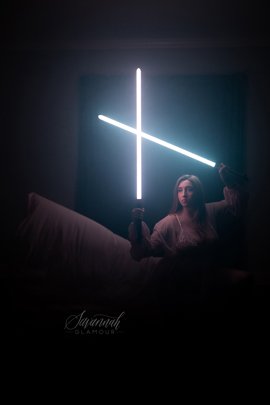 woman in gown and lingerie holding two lightsabers over her head