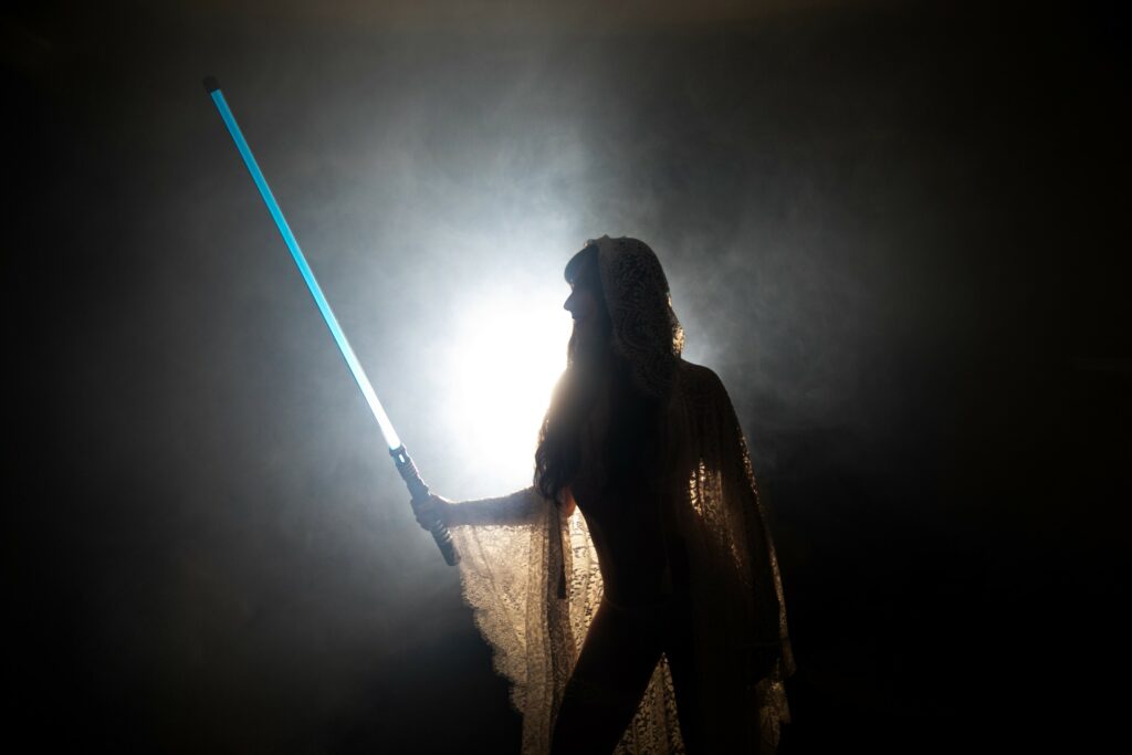woman posing in boudoir gown holding light saber