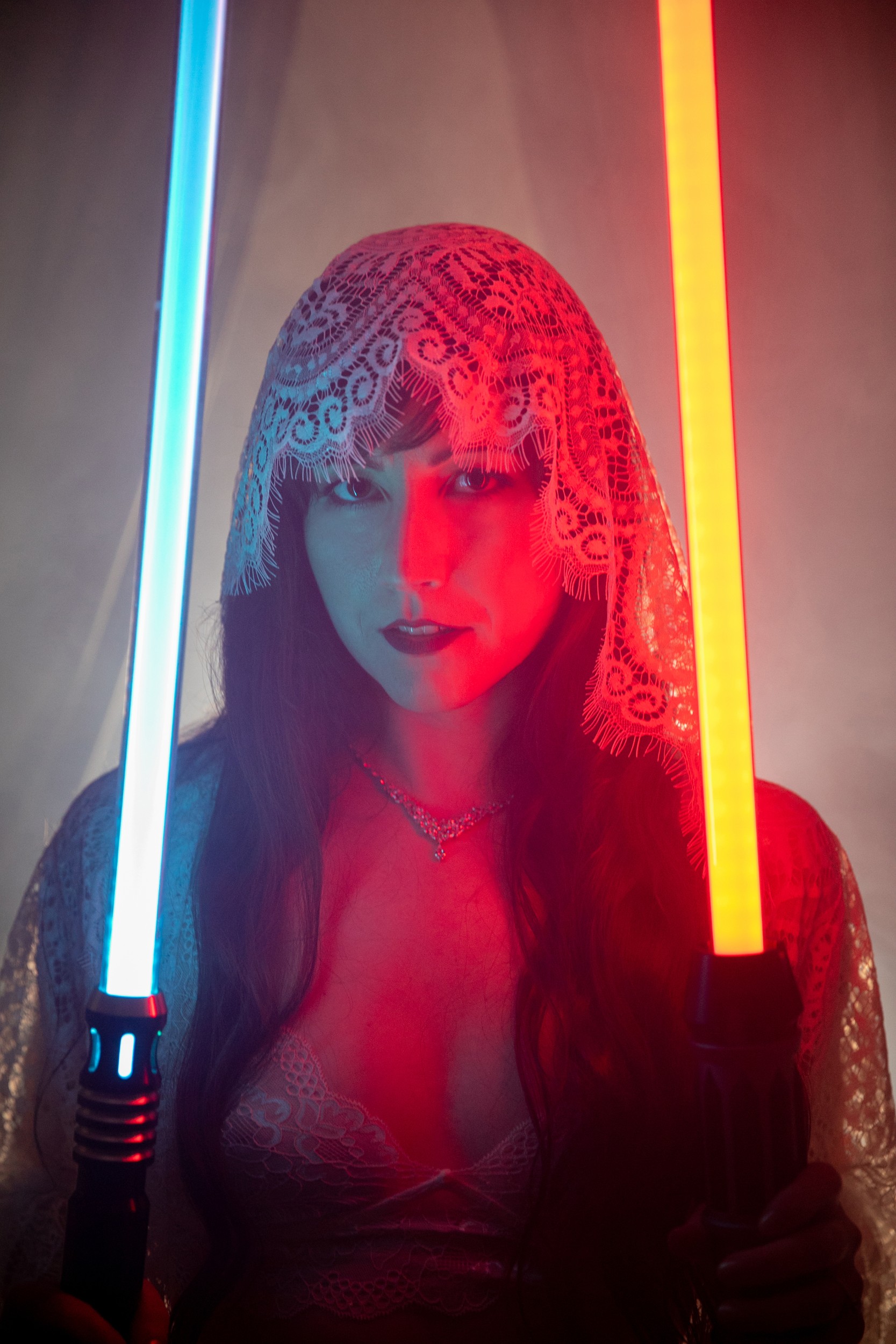 portrait of a woman wearing lace adornment holding two lightsabers