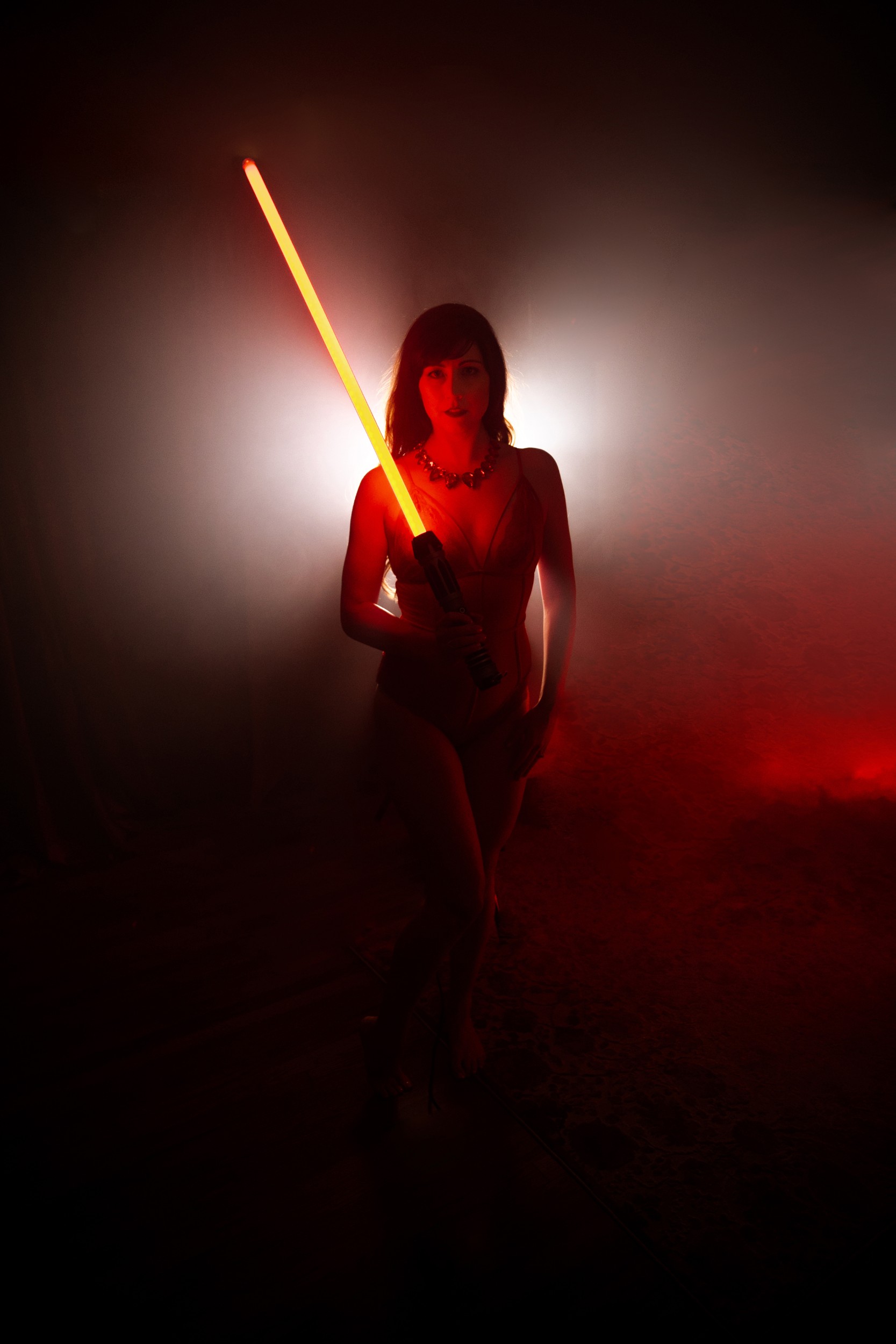 woman posing in lingerie holding a lightsaber
