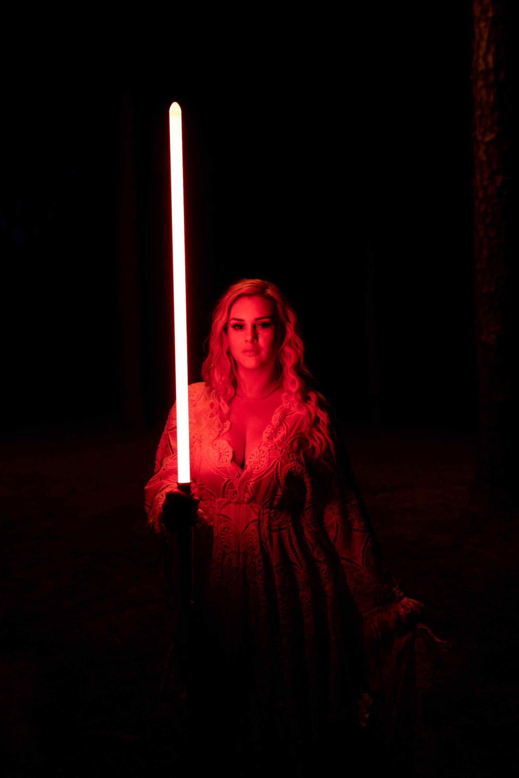 woman holding a lightsaber in the dark