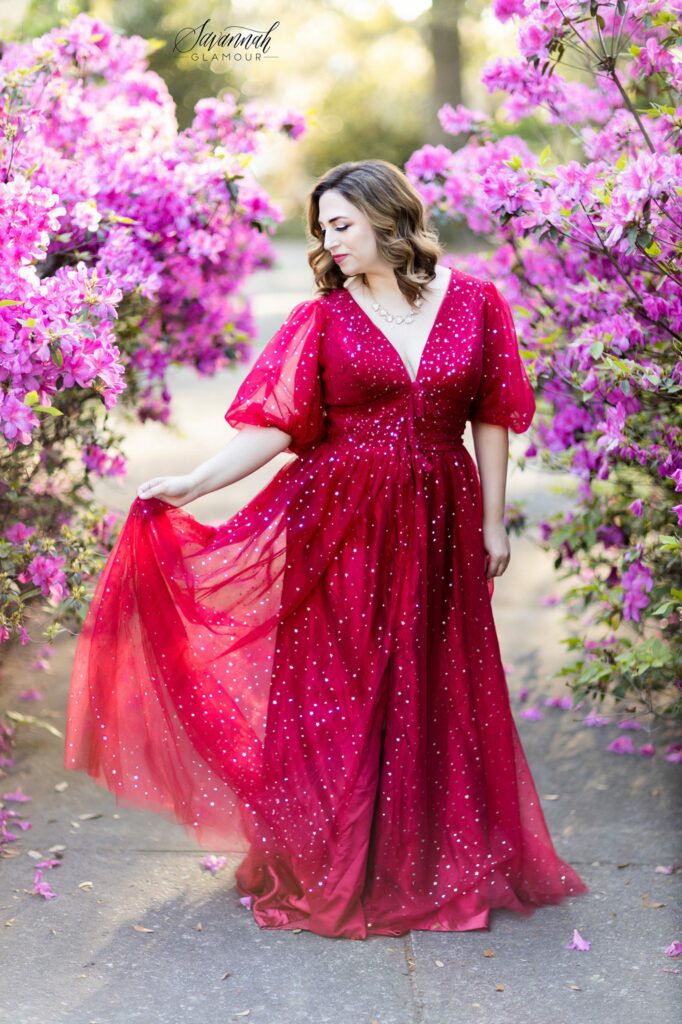 woman in a red glamour gown in front of an azalea bush in Savannah