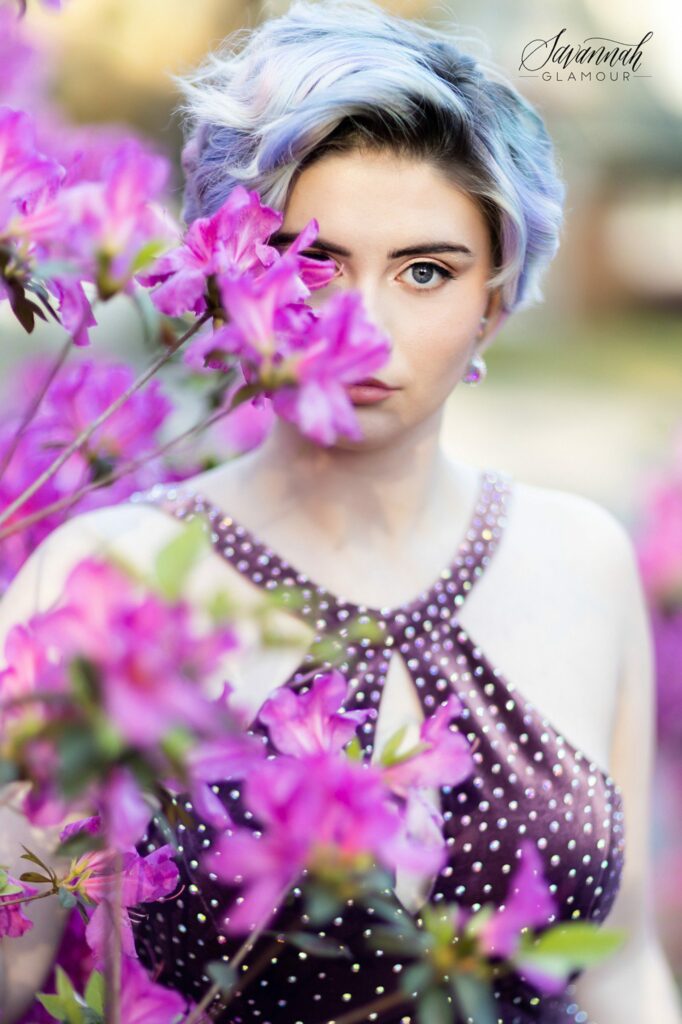 woman in a purple glamour gown peaking out behind azalea bushes in Savannah
