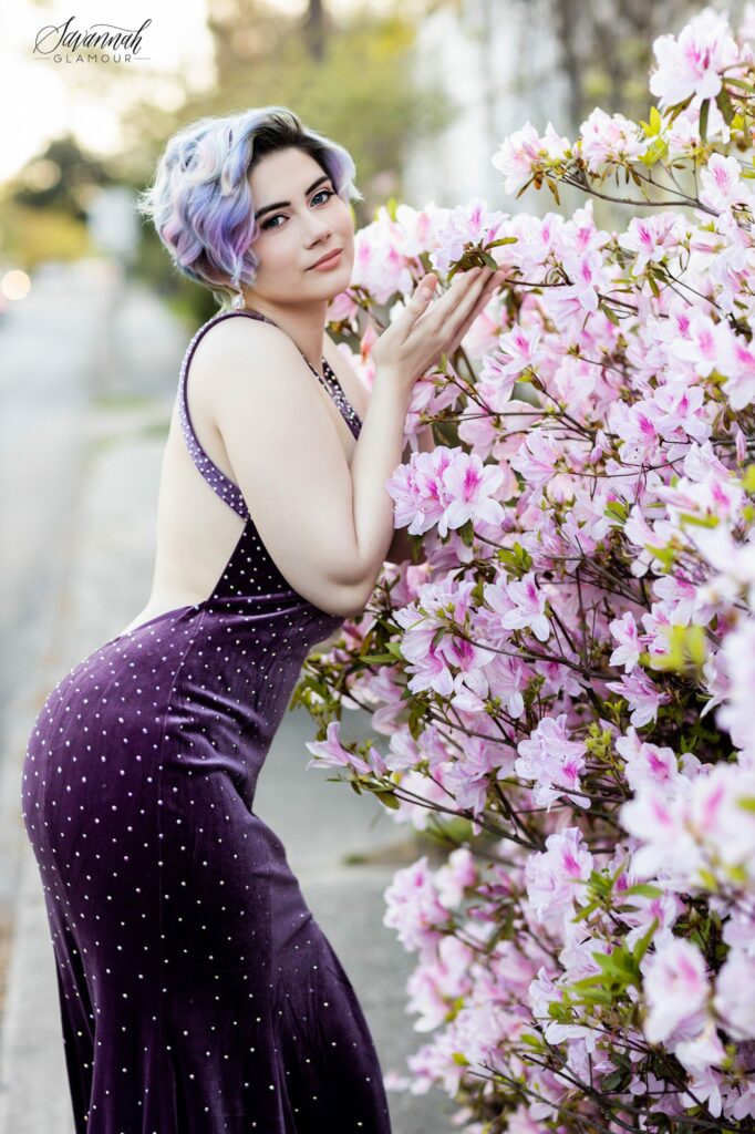 woman in a purple glamour gown in front of an azalea flower bush in Savannah