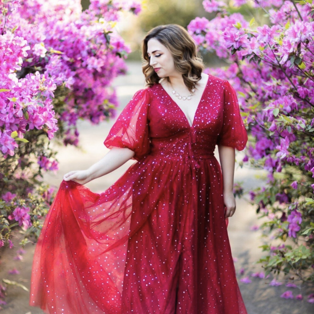 About a woman in a red dress posing in front of flowers.