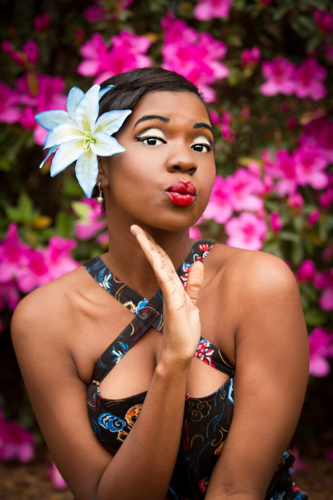 About a black woman gracefully adorned with a flower in her hair.